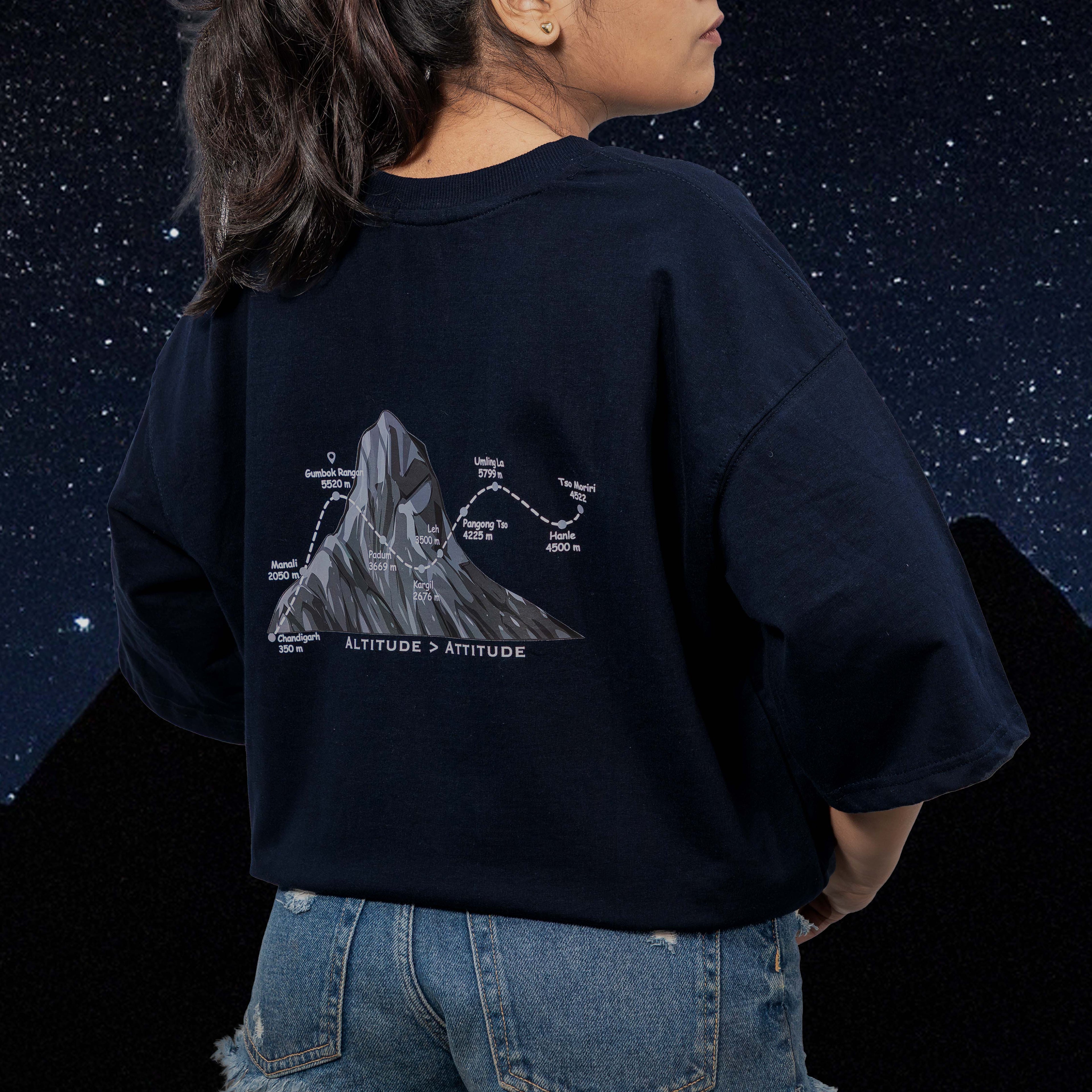 Person wearing a gumbok navy blue oversized t-shirt with a mountain graphic and text against a starry night sky.