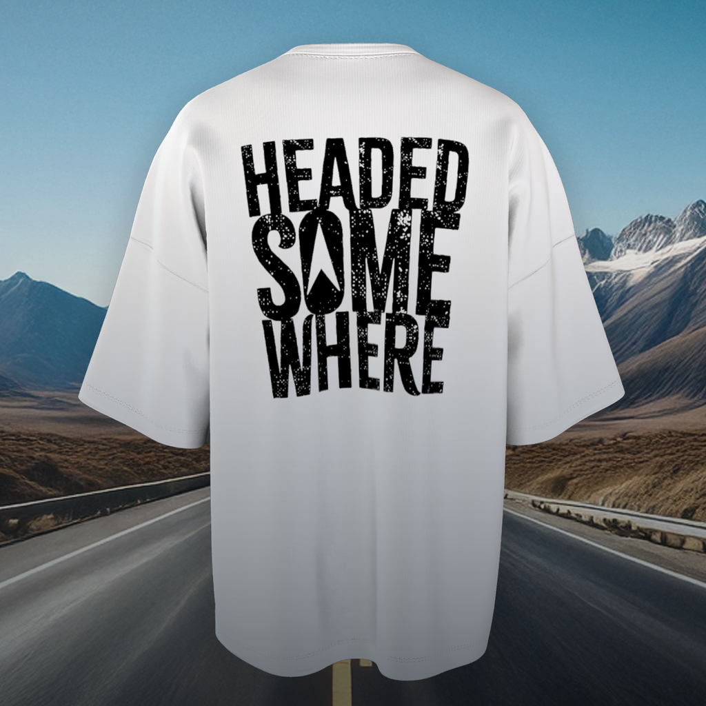 White oversized t-shirt with 'HEADED SOMEWHERE' text on a scenic road background