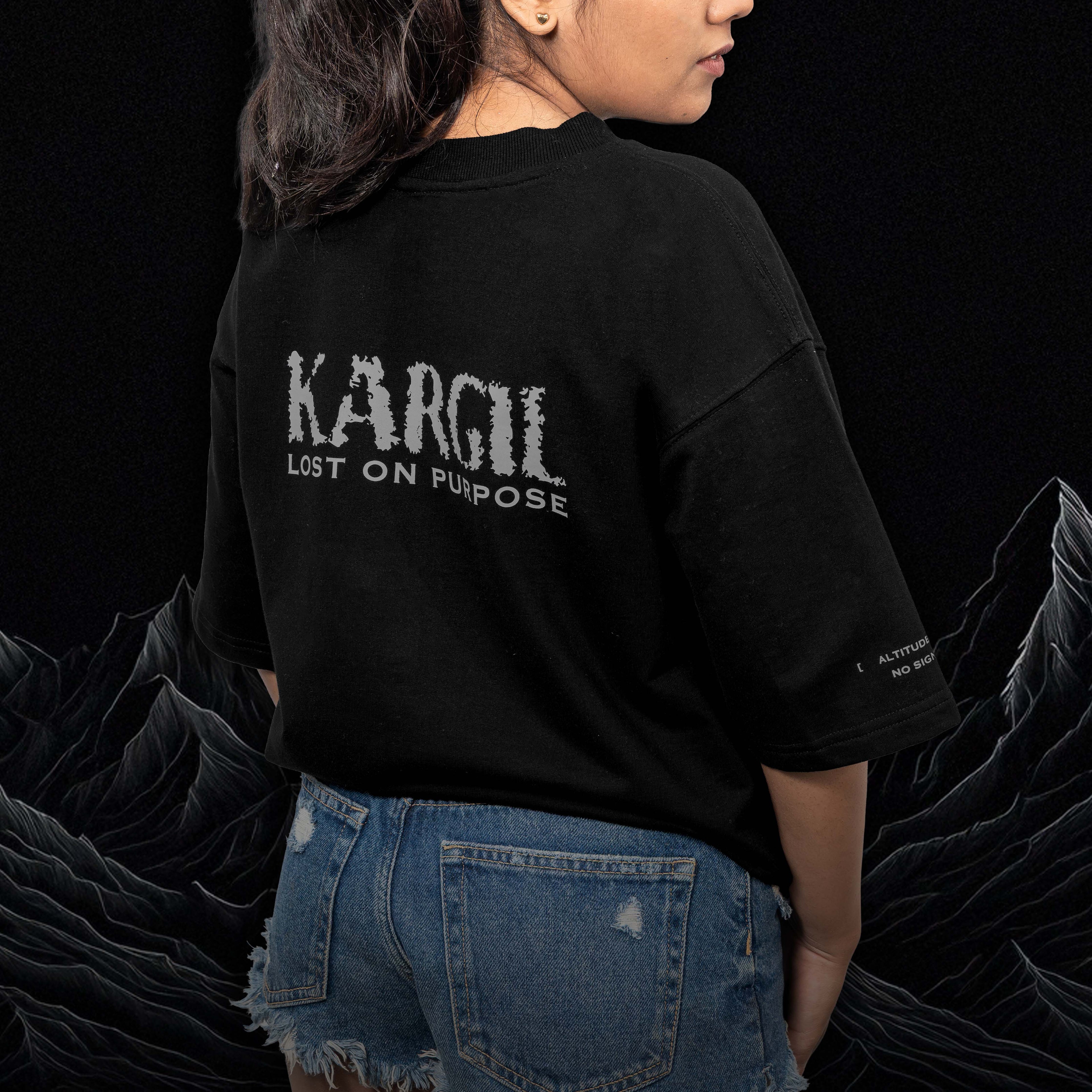 Person wearing a kargil oversized black t-shirt with 'Kargil Lost on Purpose' text, standing against a dark background.