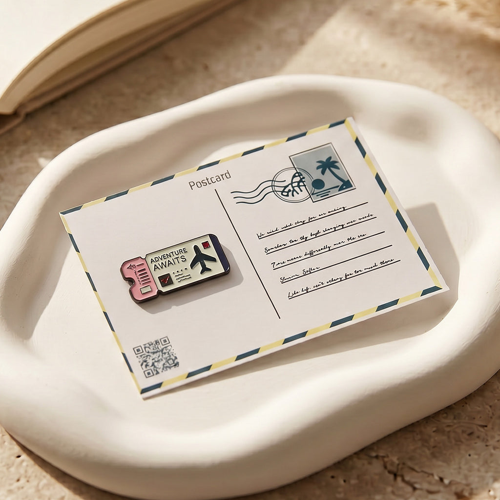 Pin with 'Adventure Awaits' design on a postcard with a palm tree stamp.