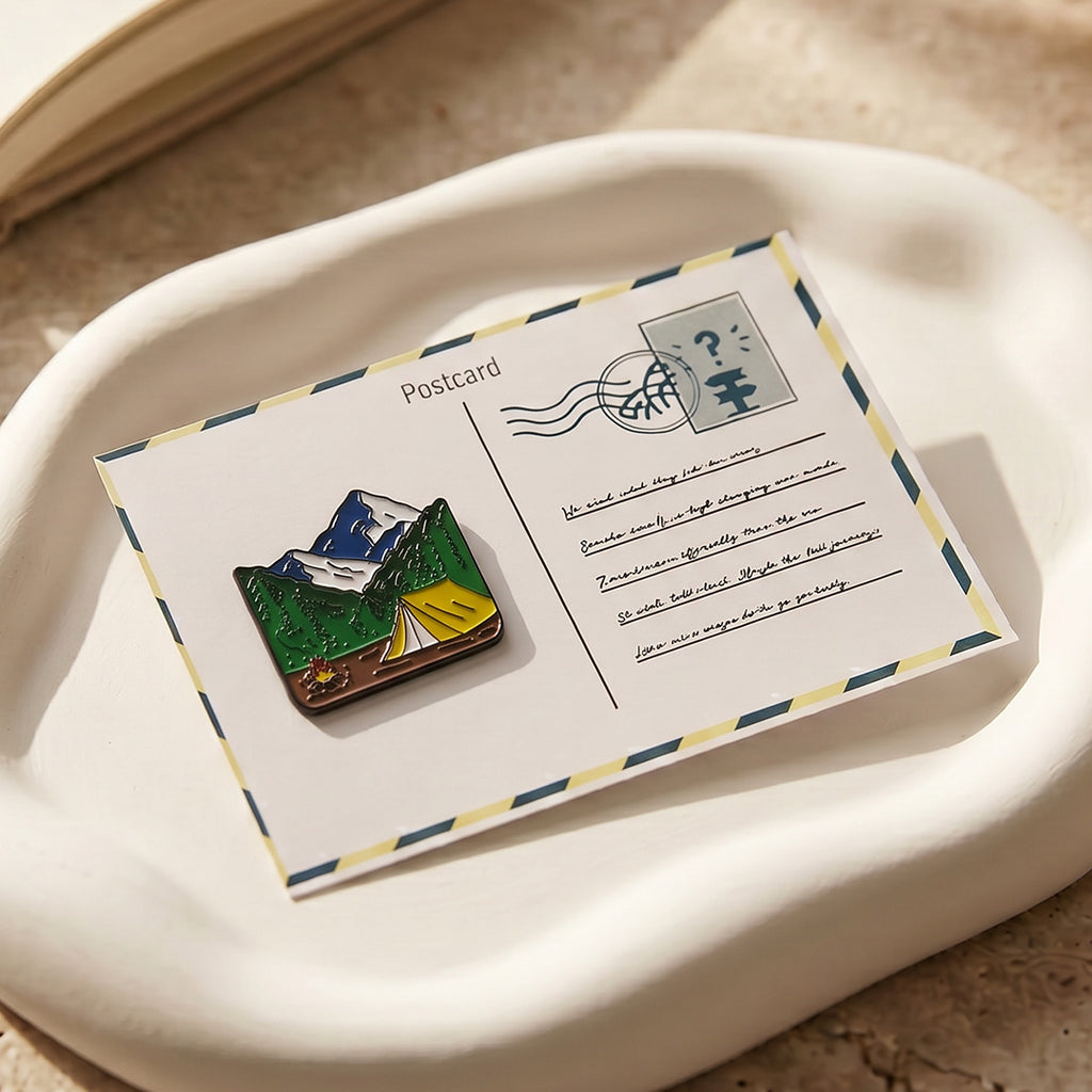 Pin with mountain design on a postcard-style card on a beige surface