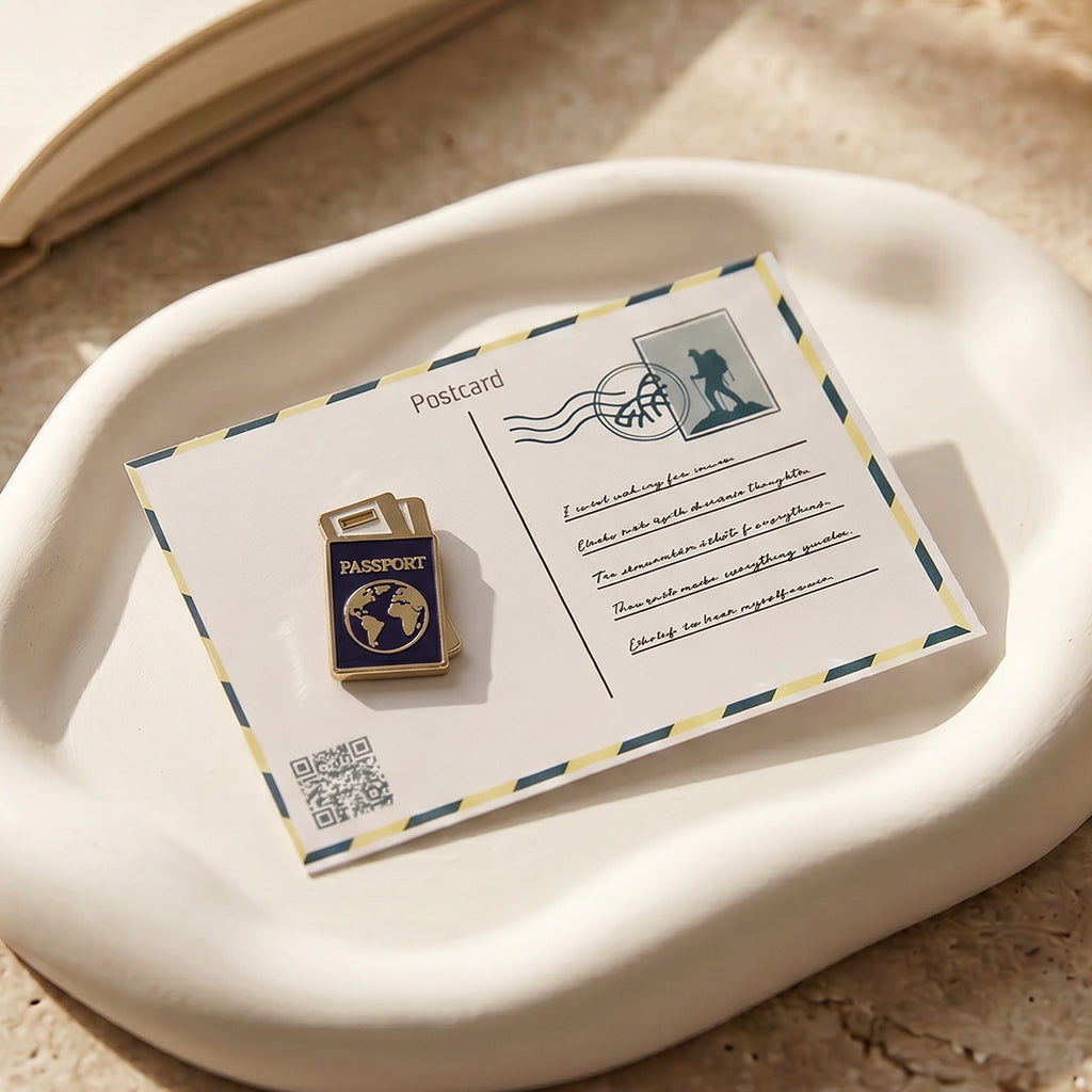 Passport-shaped pin on a postcard with a decorative envelope on a beige surface