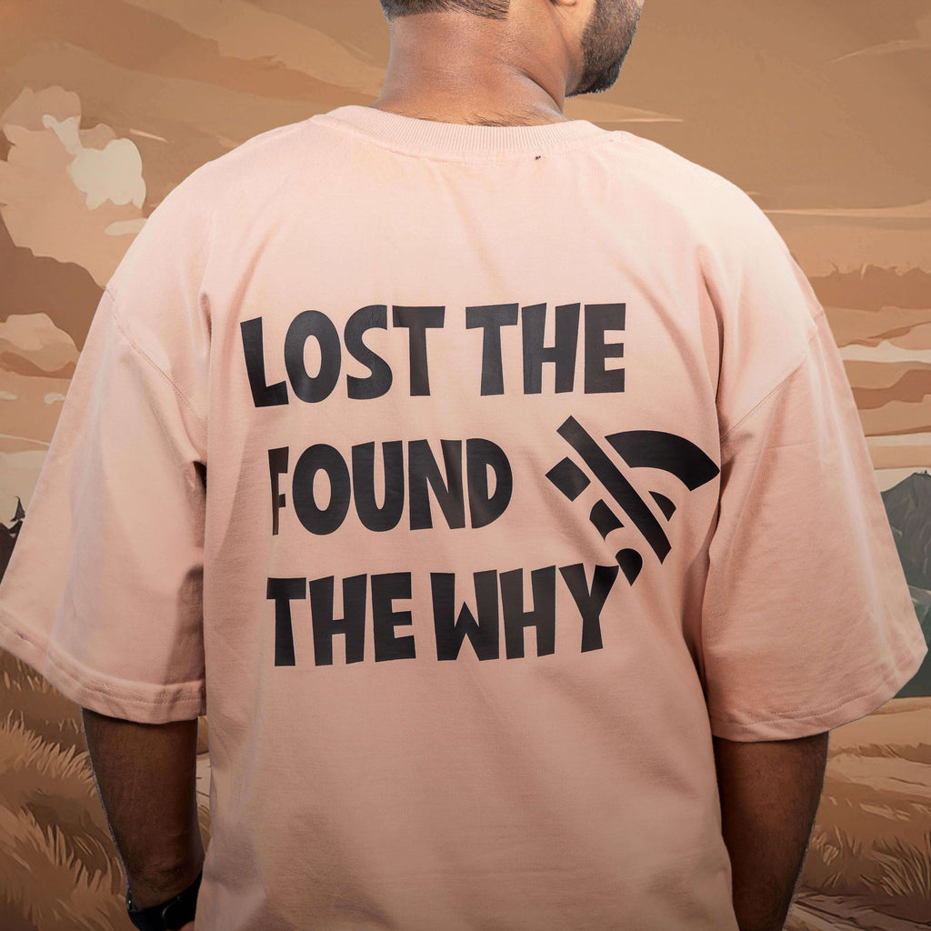 Person wearing lost the wifi beige oversized t-shirt with text on the back, standing against a desert landscape.