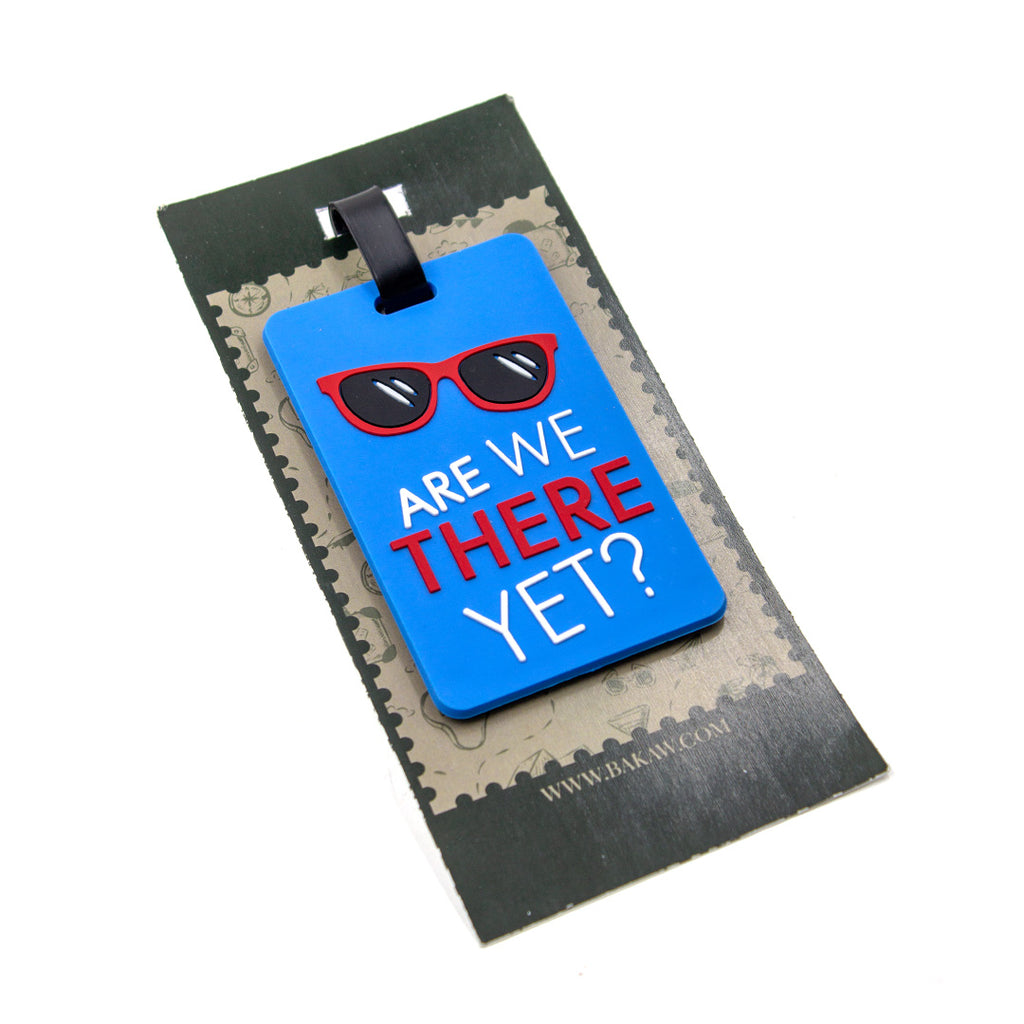 Blue luggage tag with red sunglasses and text 'Are We There Yet?' on a black and gray background