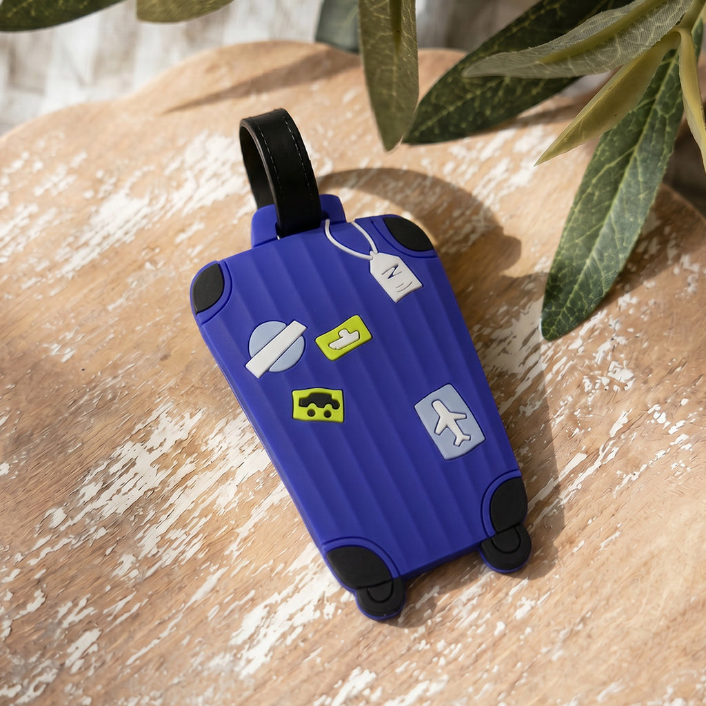 Blue suitcase-shaped keychain with stickers on a wooden surface