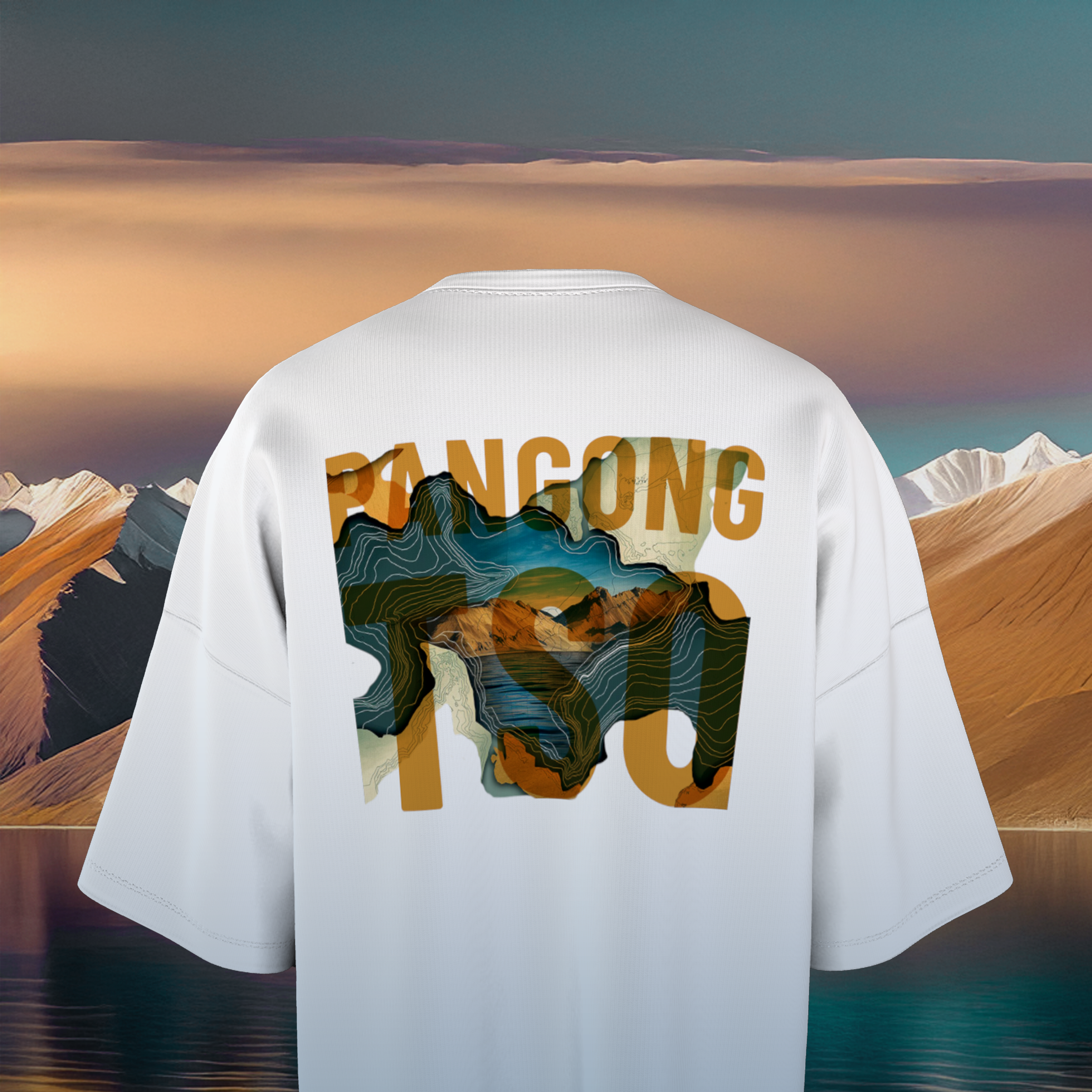 White oversized t-shirt with mountain graphic and text on the back against a desert landscape