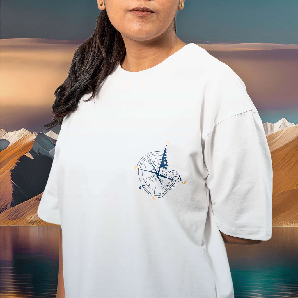 Person wearing a Pangong Tso white oversized t-shirt with a compass design against a scenic background