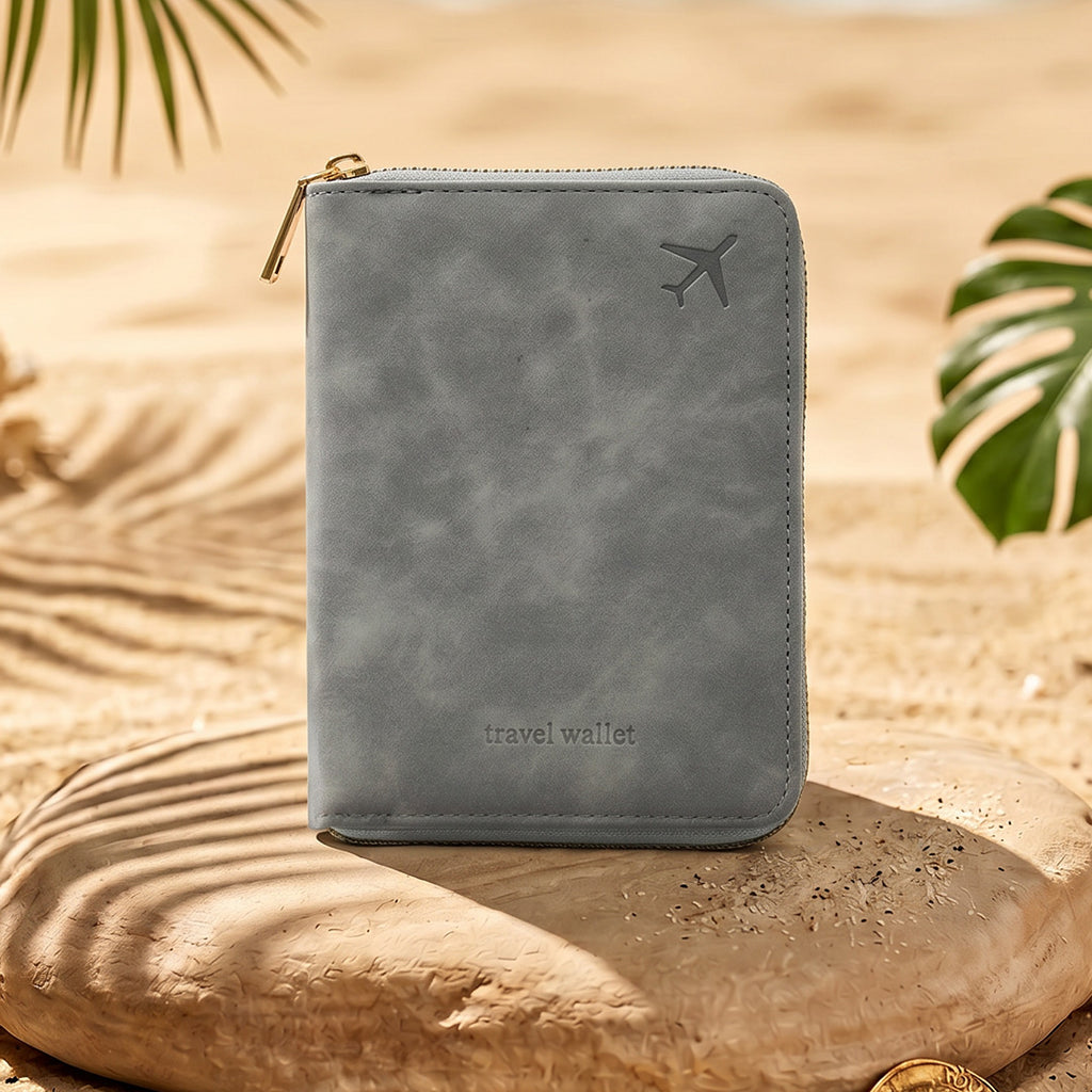 Gray travel wallet with airplane icon on a stone surface with sand and leaves in the background