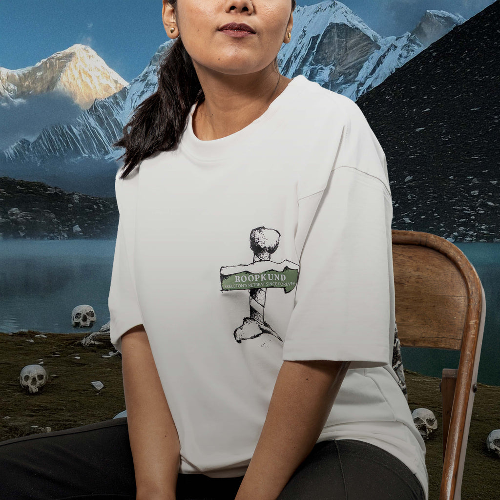 Person wearing Roopkund White Oversized t-shirt sitting on a chair against the mountain background