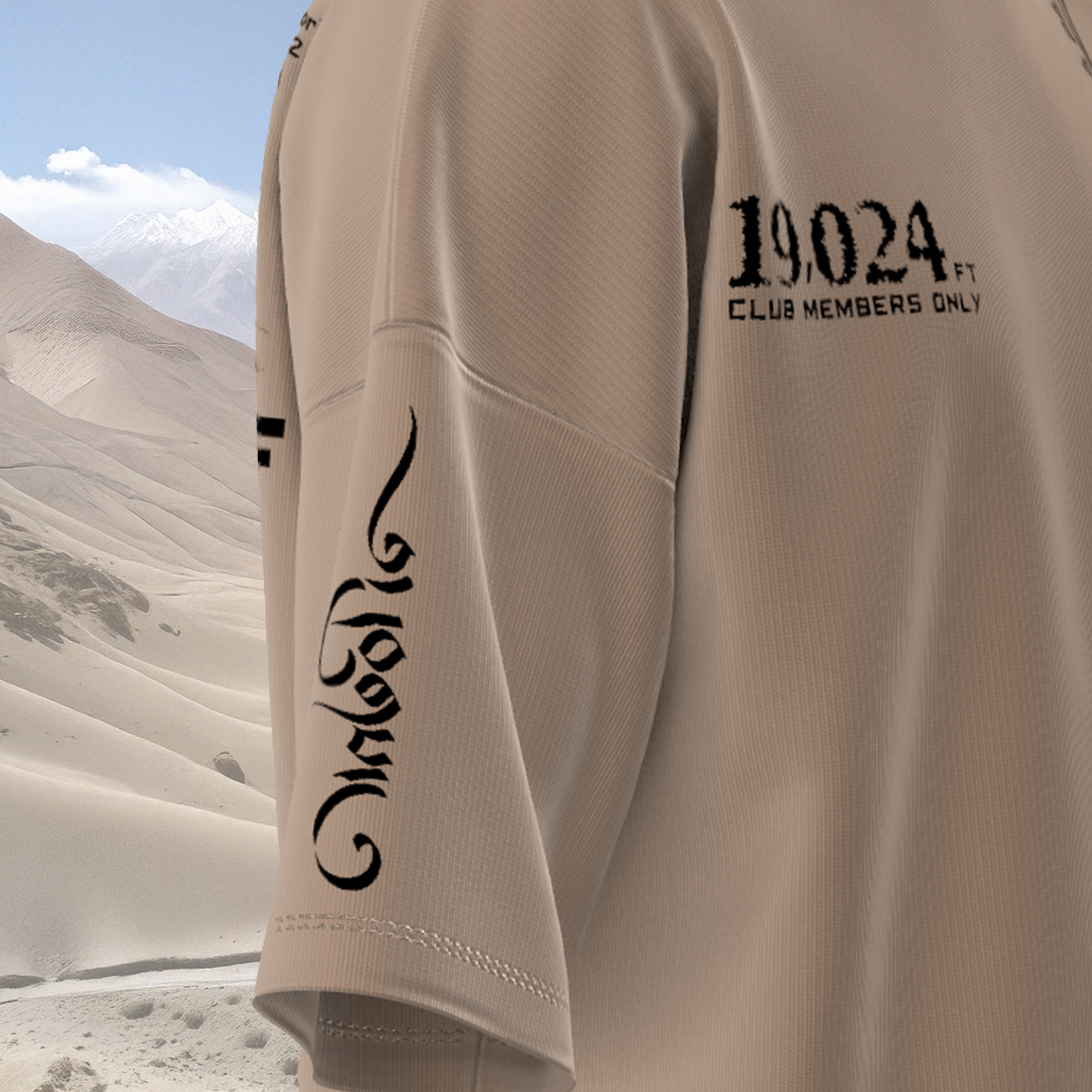 Beige oversized t-shirt with black text and design against a desert background