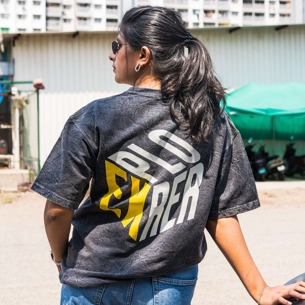 Person wearing acid wash t-shirt with 'Explorer' printed on it, standing outdoors.