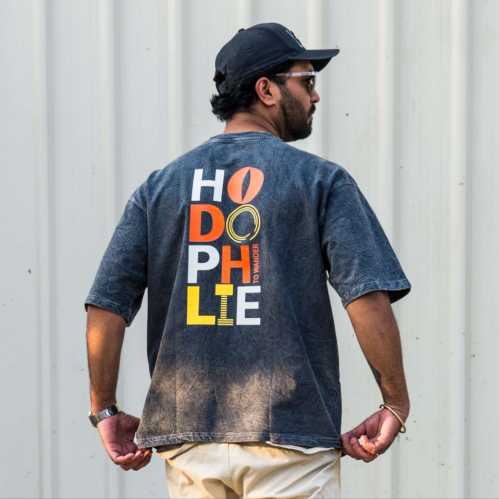 Man wearing acid wash t-shirt with hodophile text against a corrugated metal wall