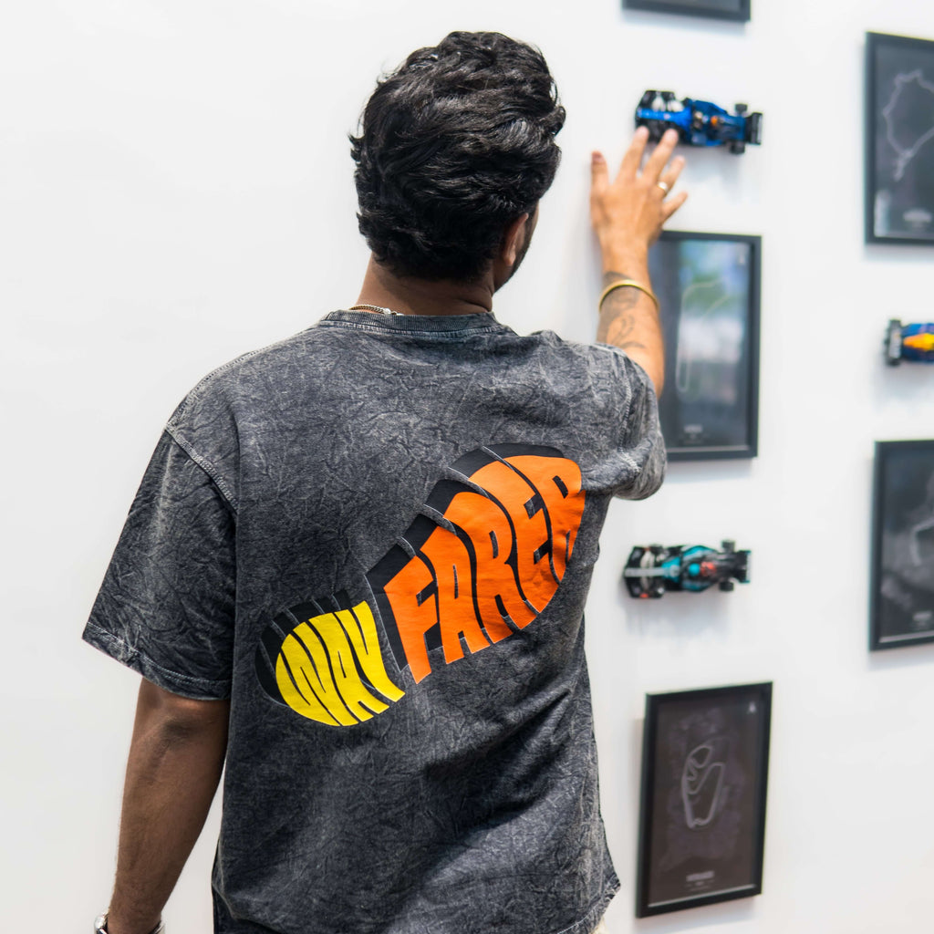 Person wearing acid wash t-shirt with 'Wayfarer' design, standing in front of a wall with framed pictures and models.