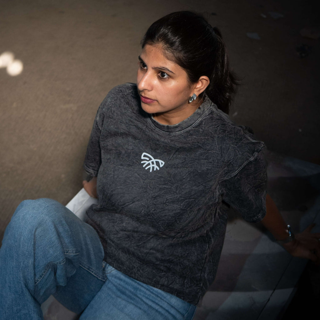 Woman wearing acid wash crew neck t-shirt with a logo sitting on a checkered surface.